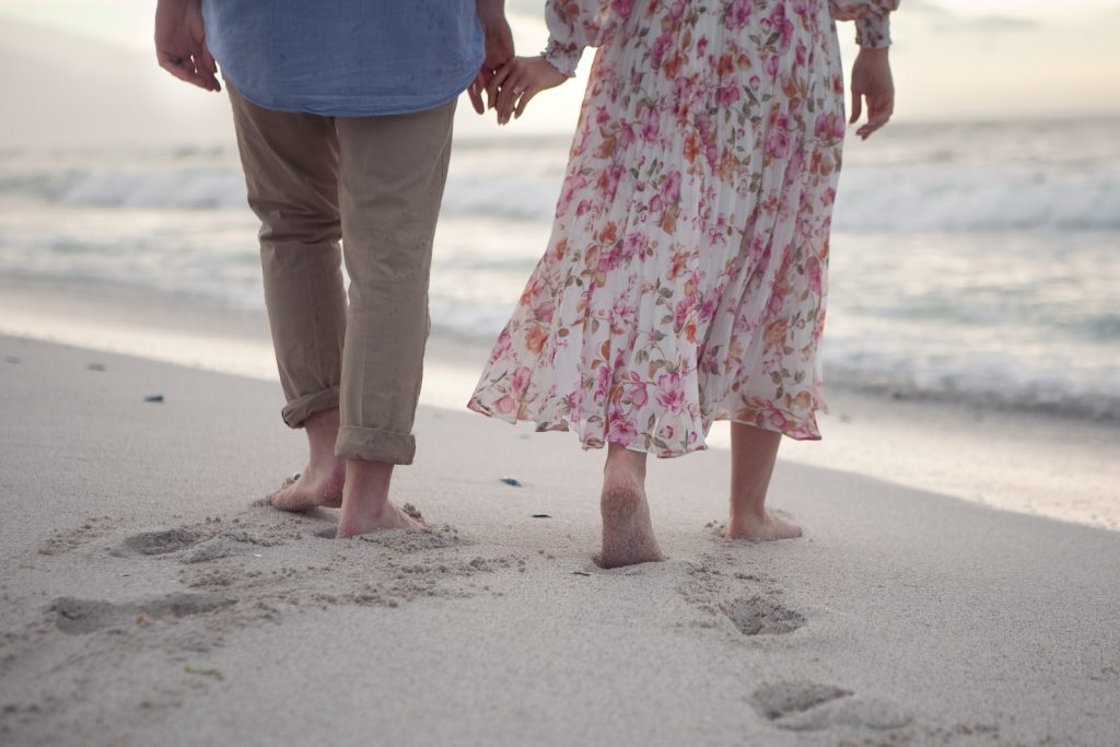 a man and a woman holding hands while walking on the beach